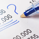 Ballpoint puts question mark by figures on financial document